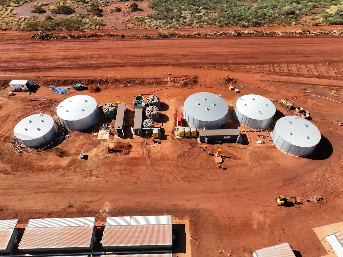 Aerial view of a MAK Water potable and sewage treatment installation with large tanks and containerized units at an iron ore mine camp in red Pilbara dirt